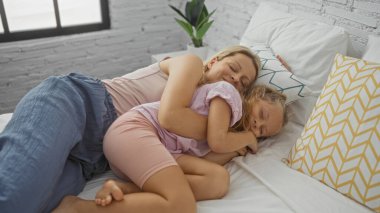 Anne ve kızı sıcak bir yatak odasında sarılıp yatıyorlar, sıcaklığı ve aile bağlarını evlerinde paylaşıyorlar..
