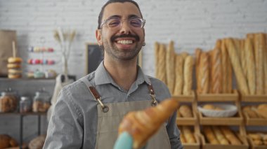 Pastanenin içinde gülümseyen bıyıklı İspanyol bir adam elinde ekmek rafları ve pastalarla bir hamur işi tutuyor..