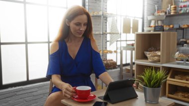 Sıcak fırının içinde kahvesini yudumlayan ve tableti karıştıran genç bir kadın..