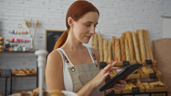 Young woman in a bakery using a tablet, surrounded by fresh bread, displaying a mix of modern technology and traditional baking setting.