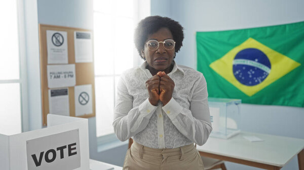 Красивая африканская американка с вьющимися волосами в комнате колледжа выборщиков в Бразилии с бразильским флагом на заднем плане