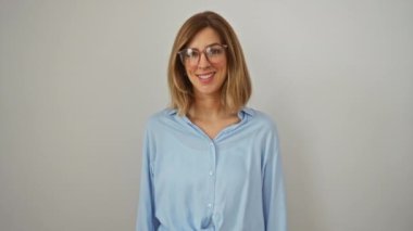 Genç bir kadın, sarışın, gözlüklü, bir numaralı parmağıyla mutlu bir şekilde duruyor, izole edilmiş beyaz arka planda gülümseyen bir yüz ifadesi sergiliyor.