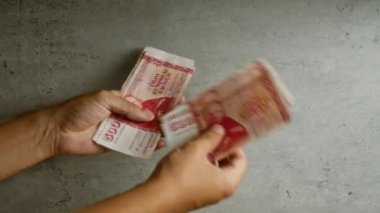 İzlanda Krona banknotlarını somut bir arkaplan karşısında sayan adam, 500 ve 1000 krona değerlerini gösteriyor.