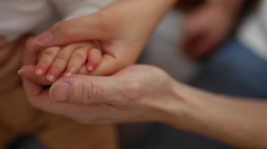 Bir kadın, sıcak ve sevgi dolu bir aile ortamında bebeğinin elini tutuyor ve aile bağlarını içeride gösteriyor..