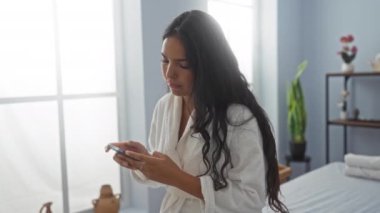 Sükunetli bir spa odasında akıllı telefon kullanan bir kadın, refah inzivası gösteriyor.