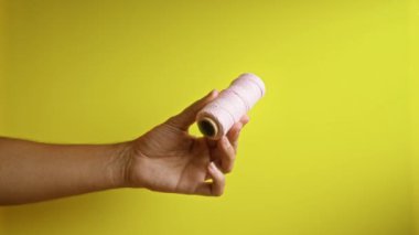 Sarı arka planda pembe iplik tutan adam zanaat gereçlerini ve sanatsal becerilerini gösteriyor.