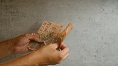 Romen lei parasını beton duvar arkasında tutan ve sayan adam