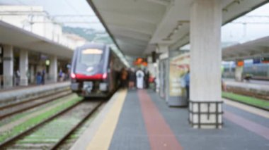 Yoğun bir istasyona varan trenin bulanık görüntüsü. Odaklanmış yolcular peronda kentsel bir ortamda..