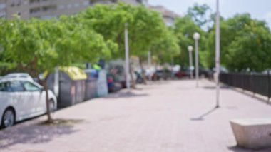 Ağaçlı, arabalı ve güneşli bir günde Bokeh etkisi yakalayan insanların olduğu açık şehir manzarası bulanık.