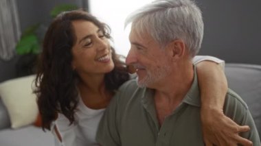 Orta yaşlı bir çift, sıcak bir oturma odasında sevgi dolu bir şekilde kucaklaşıyorlar. Kapalı alanlarda sevişmekten hoşlanan erkek ve kadın arasındaki duyguları sergiliyorlar..