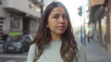 Şehirdeki şehir caddesinde duran bir kadın esmer saçlı ve sakin yüzlü genç bir güzelliği sergiliyor. Gün boyunca şehir ortamında..