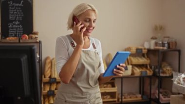 Telefonla konuşan ve fırının içinde tablet kullanan genç bir kadın.