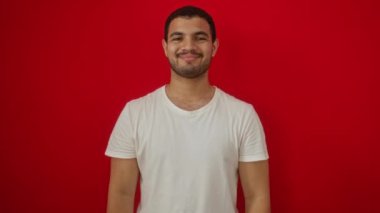 Beyaz tişört giyen genç İspanyol adam ayakta duruyor ve elleri ve parmakları ile çerçeve yapıyor; izole kırmızı arka plan üzerinde yaratıcılık ve fotoğrafçılık mutlu konsept