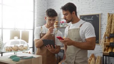 Fırında birlikte çalışırken tablet ve telefon kullanan erkek fırıncılar.