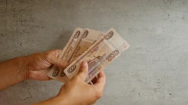 Elleri tutan ve sayan Rus rublesi banknotları beton bir arka planda