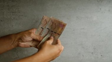 Kolombiya pezosu sayan, somut arka planda para tutan, nakit işleme vurgulayan bir adam
