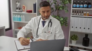 Doktor, tıbbi ekipman ve bitkilerle çevrili klinikteki hastayla konuşuyor. Profesyonel danışma ortamında beyaz önlük ve steteskop giyiyor..