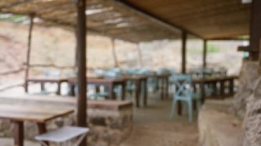 Açık hava restoranının bulanık görüntüsü. Boş masaları ve Mallorca 'da ahşap bir gölgeliğin altında sandalyeleri var.