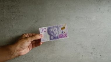 Elinizde somut bir arkaplana karşı 20 İsveç kronu banknotu tutarken, İsveç 'te mali bağlamda para birimi hakkında net detaylara odaklanıyorsunuz..