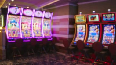 Blurry view of casino slot machines indoors in las vegas with vibrant lights and empty chairs creating an atmospheric gambling environment.