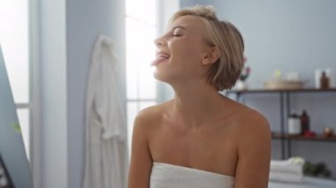 Güzel sarışın kadın güzellik salonunda gülüyor, kısa saçlı ve omuzlarında havluyla.