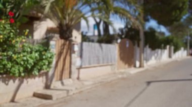 Mallorca 'da güneşli bir sokak sahnesinin bulanık arkaplanı, dağılmış evleri, palmiyeleri ve çiçekleri olan İspanya' nın bokeh etkisi yaratan.