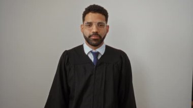 Önlüklü yargıç, genç İspanyol adam ayakta duruyor, parmaklarının arasından bakıyor, mutlu ve gülümsüyor izole beyaz arka planda.