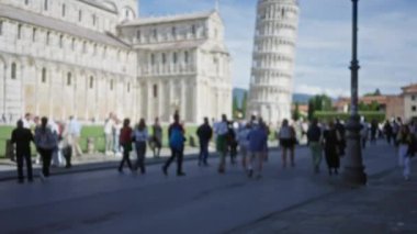 Turistler Pisa 'nın ikonik eğimli kulesinin etrafında toplanarak güzelliğini yakalıyorlar. Bu arada bulanık figürler İtalya' nın tarihi anıtının kalbinde dinamik ve hareketli bir sahne oluşturuyor..