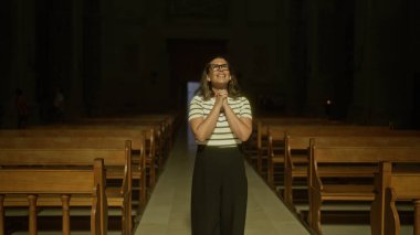 Güzel, genç bir İspanyol kadın loş bir İtalyan kilisesinde dua ediyor, dingin bir Hıristiyanlık anını somutlaştırıyor..