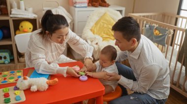 Anne ve baba, küçük oğullarını sevgi dolu bir şekilde yatak odasındaki rahat oyuncaklarla birbirine bağlıyor. Beşik ve yumuşak ışıklandırmayla güçlendirilmiş sıcak bir aile ortamı yaratıyorlar..
