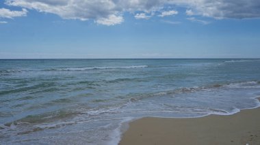 Salento, puglia, İtalya 'da bulutlu bir gökyüzünün altında berrak dalgaların ve pescoluse plajının sakin bir görüntüsü..