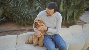 Kentsel park ortamında fino köpeğiyle bağ kuran olgun bir İspanyol.