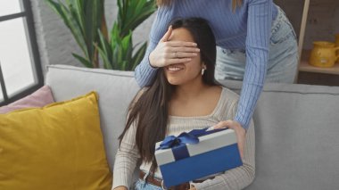 İki kadın kapalı bir koltukta özel bir anı paylaşırken biri diğerini hediye kutusuyla şaşırtıyor. Arkadaşlık ve şefkat tasvir ediyorlar..