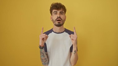 Sakallı ve dövmeli İspanyol bir adam, sarı arka planda izole edilmiş..