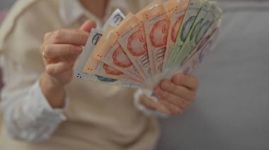 İçerideki orta yaşlı bir kadın parasına odaklanmış Türk lirası sayıyor.