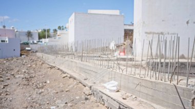 Temiz bir gökyüzünün altında beton yapılar ve takviye çubukları olan bir inşaat alanının bulanık arka planı