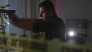 Karanlık bir olay yeri soruşturmasında elinde silah ve el feneri tutan İspanyol bir adam.