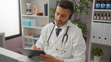 Beyaz önlüklü ve steteskoplu bir adam hastane ofisindeki panoya tıbbi malzemeler ve bitkilerle çevrili bir şekilde modern sağlık hizmetleri sergiliyor..