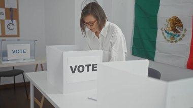 Orta yaşlı İspanyol bir kadın, demokratik ve vatandaşlık görevlerini simgeleyen Meksika bayrağıyla süslenmiş bir odada oyunu kullanıyor..