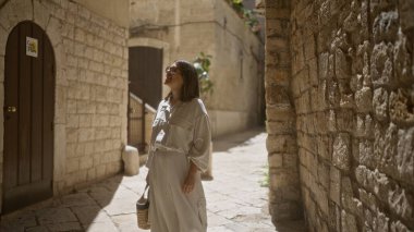Genç İspanyol kadın eski şehir sokaklarında geziniyor. Bari, İtalya 'da. Antik taş duvarlara karşı sıcak güneş ışığında güneşleniyor..