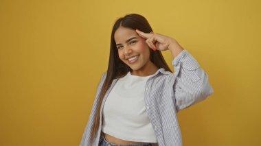 Parlak sarı bir arka plana gülümseyen bir kadın, sıradan çizgili bir gömlekle neşeli ve olumlu bir ifade sergiliyor..