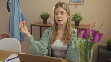 Genç bir kadın evinde çiçeklerle masasında farkındalık pratiği yapıyor..