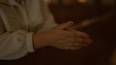 Genç bir kadın, loş bir İtalyan kilisesinde elleri sımsıkı bağlı dua ediyor. Sadakatini ve inancını yansıtıyor..