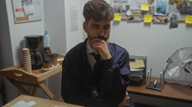 Dedektifin ofisinde sakallı, düşünceli bir adam. Etrafı ipuçları ve kanıtlarla çevrili..