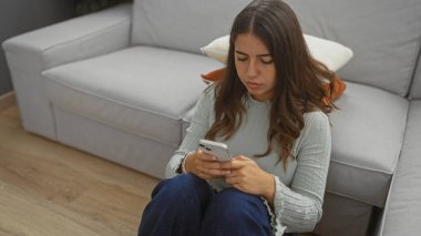 Oturma odasında oturan kadın akıllı telefon kullanarak modern yaşam tarzını ve evdeki iletişimi resmediyor..