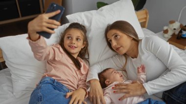 Anne ve kızları bir apartman dairesinde birlikte rahatlıyor, bir bebek ile evde selfie çekerken sevgi ve aile bağlarını kucaklıyor..