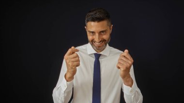 Genç adam, özgüvenli bir gülümseme ve resmi kıyafetle siyah arka plana karşı para hareketi yapıyor. Başarı, finans ve zenginliği dramatik bir şekilde temsil ediyor..