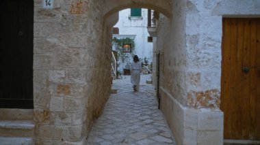 Genç bir İspanyol kadın polignano 'da tarihi bir sokakta yürüyor. Bir kısrak, puglia, İtalya, taş kemerler ve geleneksel mimari..