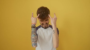 Sakallı ve dövmeli İspanyol bir adam sarı arka planda stres gösteriyor.