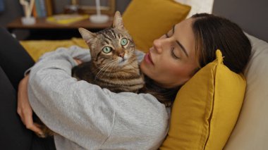 Genç bir İspanyol kadın, evcil kedisiyle sıcak bir yatak odasında bir yatakta sarılır ve bir bağ kurma ve rahatlama anı yakalar..